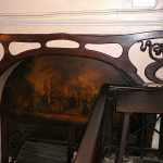 Abertura del pasaje de Escudellers, con montante pintado con motivo costumbrista y dintel de madera decorado con sinuosidades 