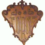 Escudo de madera trabajada con el nombre del fundador